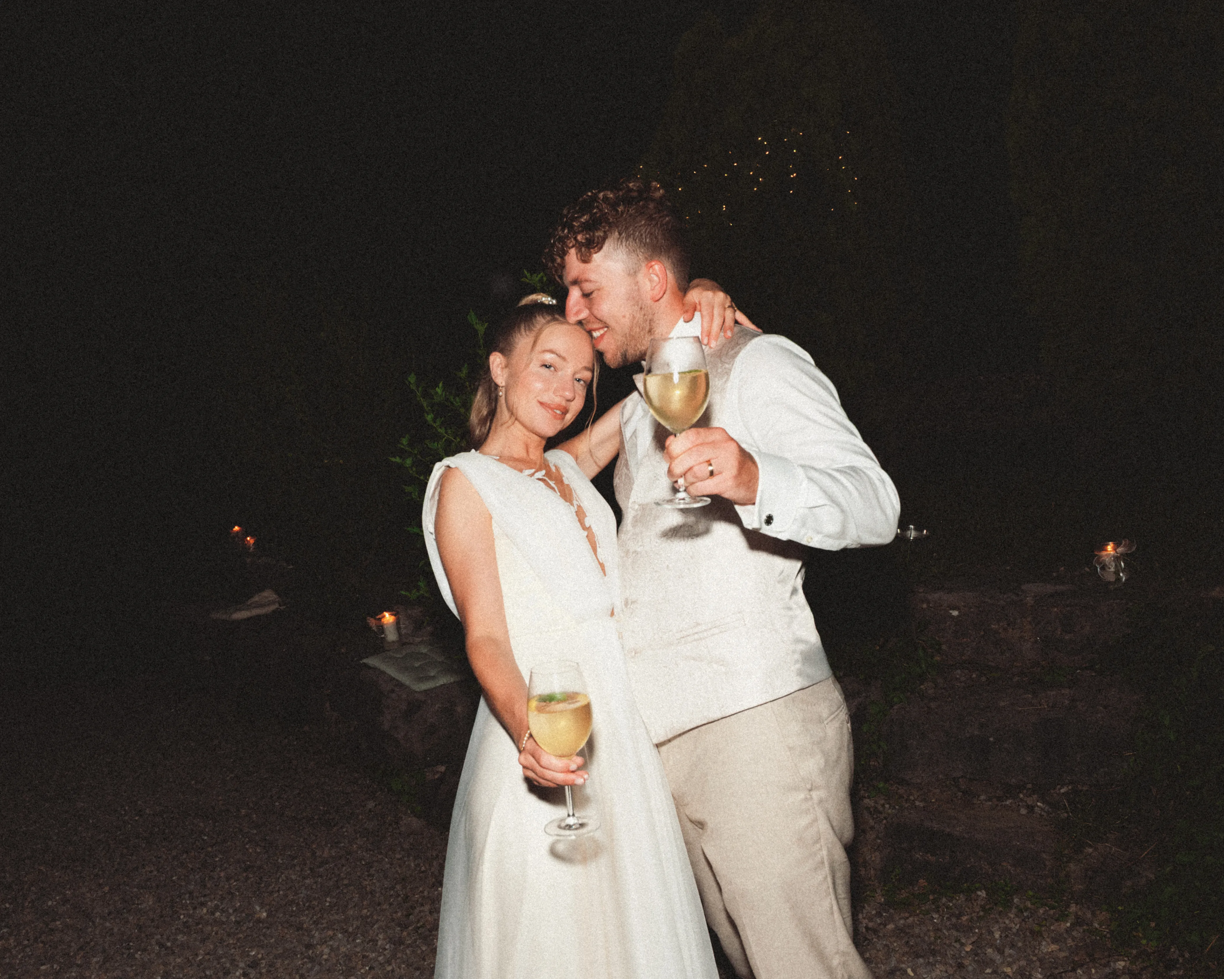 Franziska und Daniel umarmen sich am Abend mit Weingläsern.