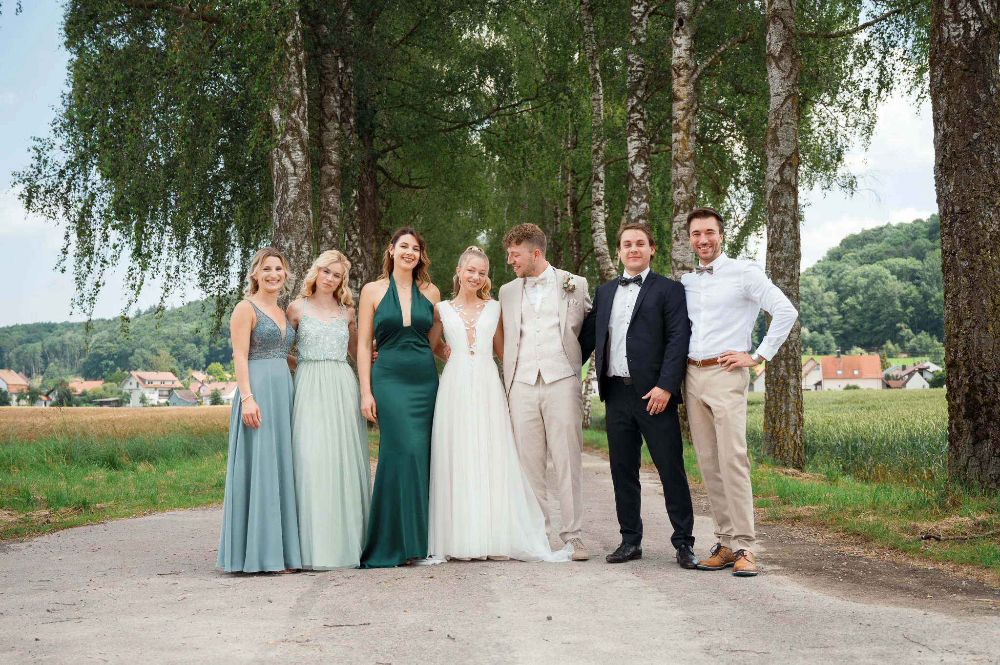 Franziska und Daniel stehen mit ihrer Hochzeitsgesellschaft auf einer Straße.
