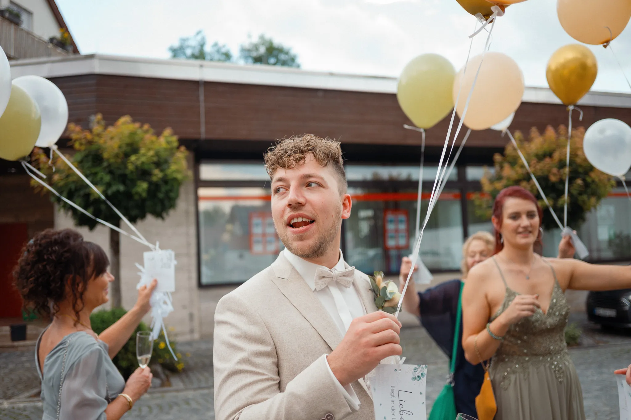 Daniel blickt lachend zu den Luftballons hinauf.