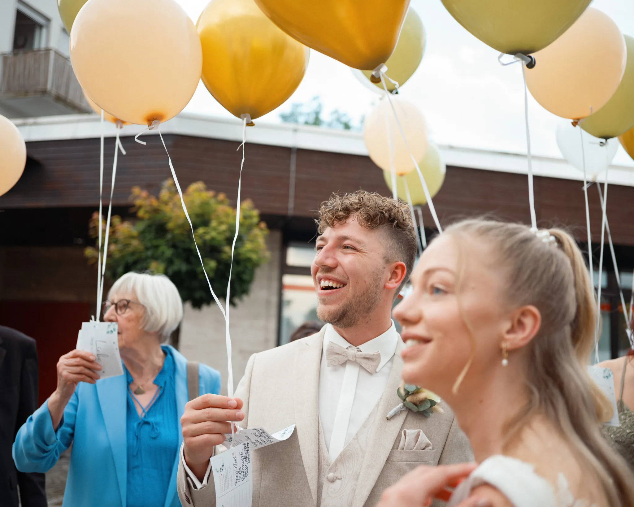 Franziska und Daniel lachen zwischen ihren Gästen und Luftballons.