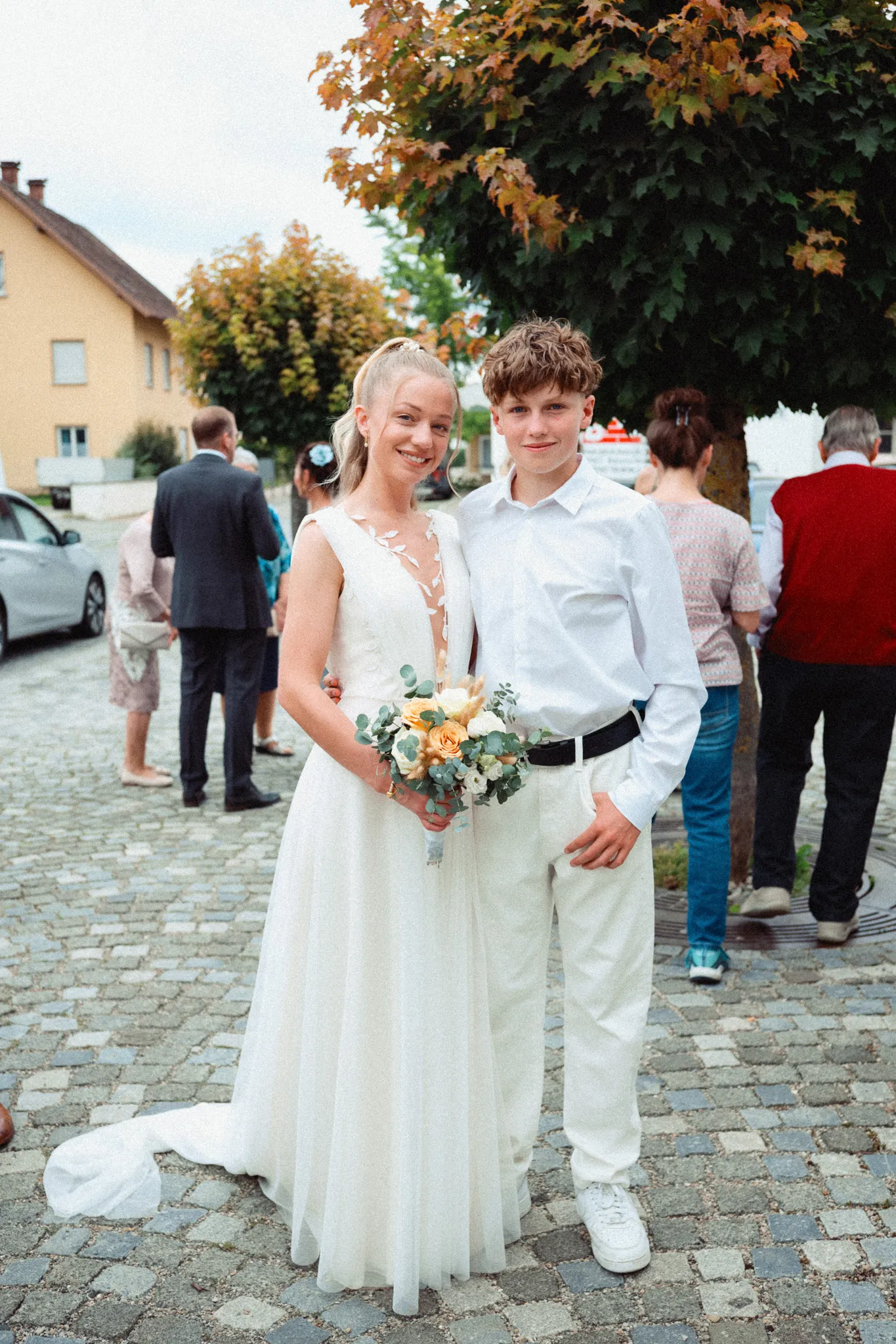 Franziska steht mit Brautstrauß neben einem jungen Gast.