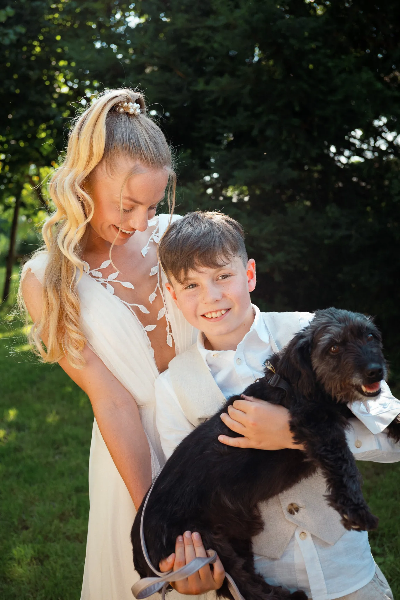 Franziska steht mit einem Jungen und einem kleinen Hund im Garten.