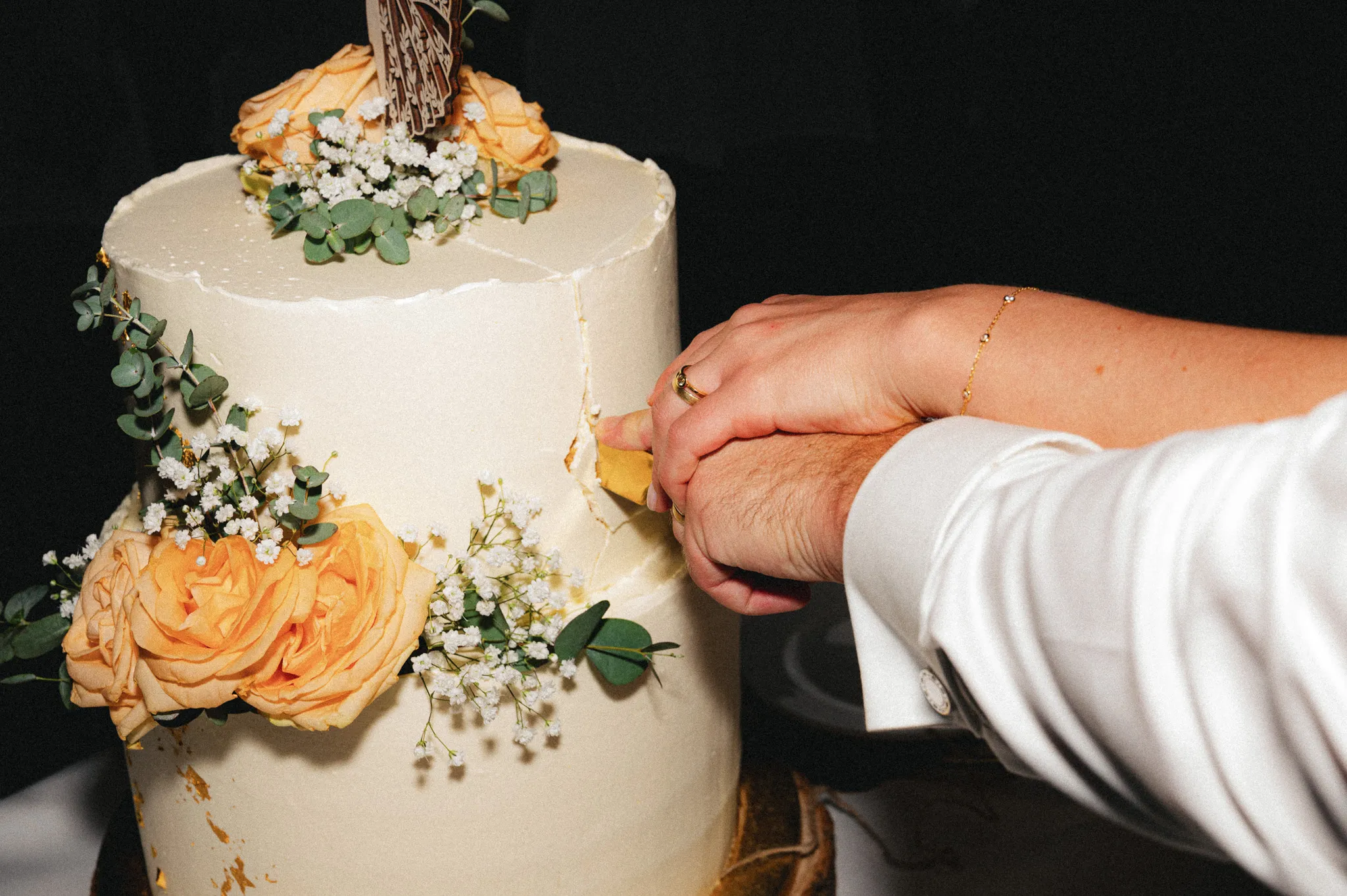 Ein Messer schneidet die mit Blumen verzierte Hochzeitstorte an.