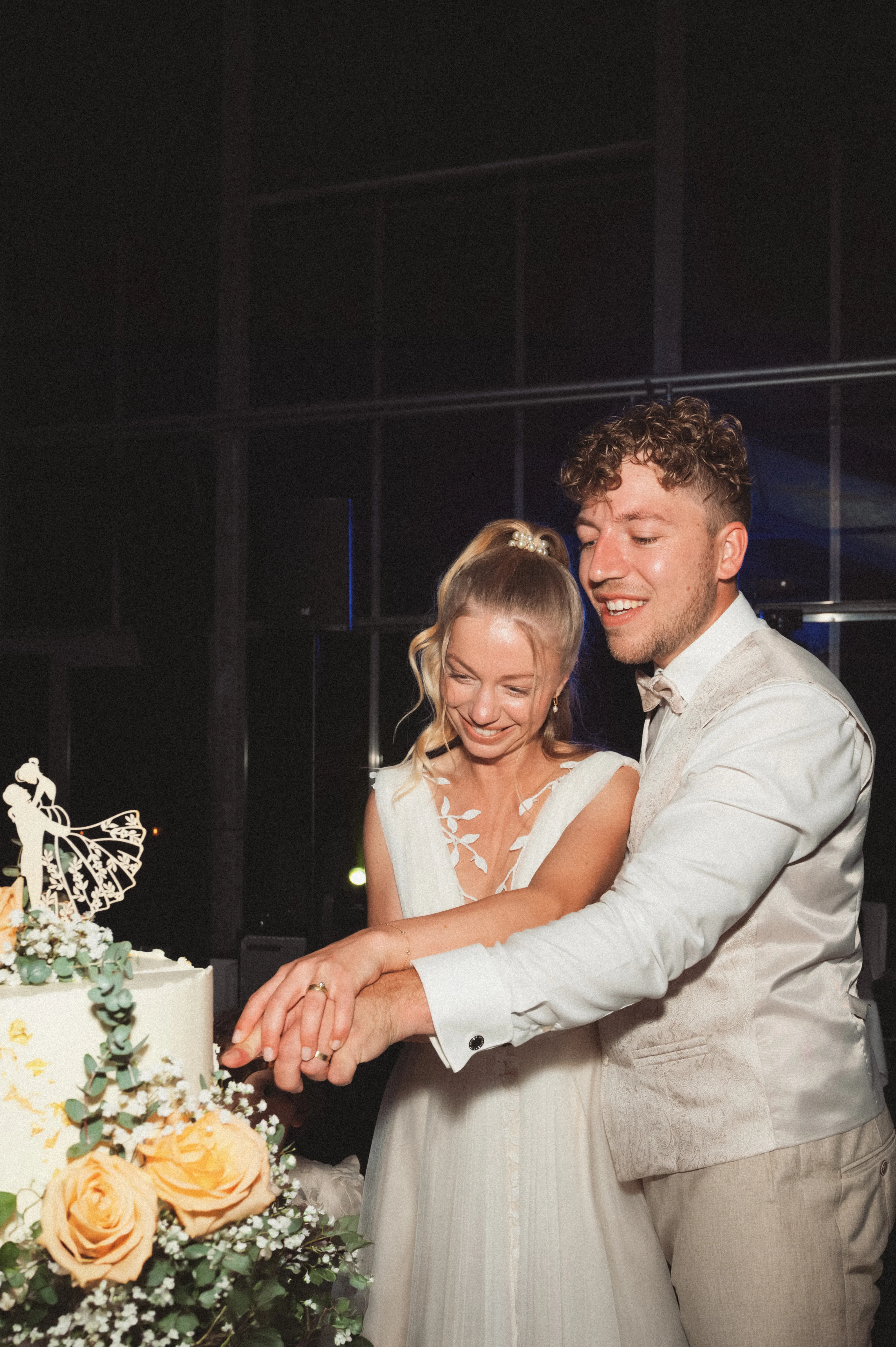 Ein Brautpaar schneidet gemeinsam die Hochzeitstorte an.