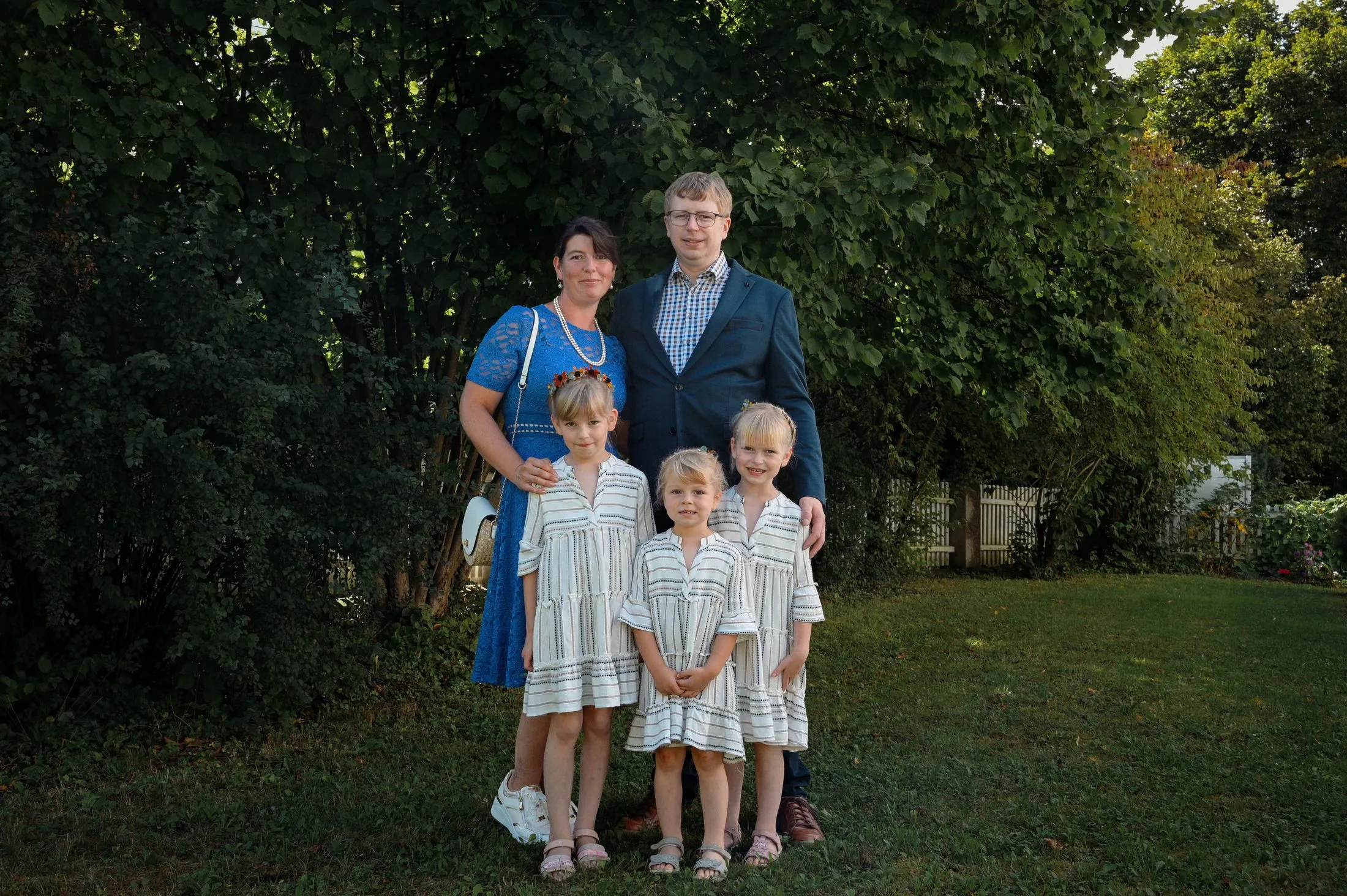 Kinder und Erwachsene stehen für ein Gruppenbild im Garten.
