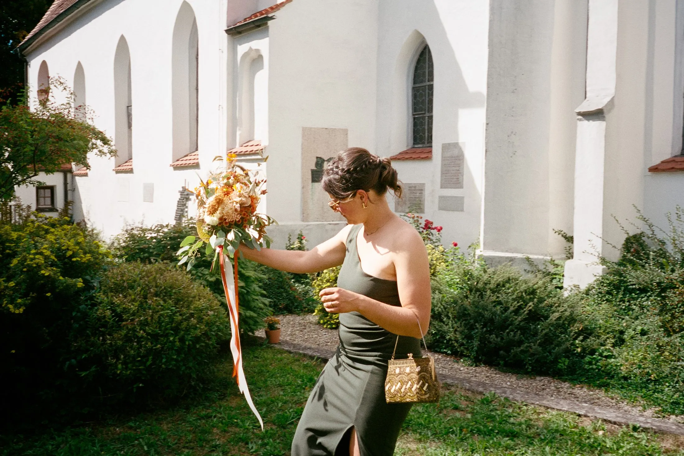 Eine Frau richtet Details von Lisas Kleid vor der Kirche.