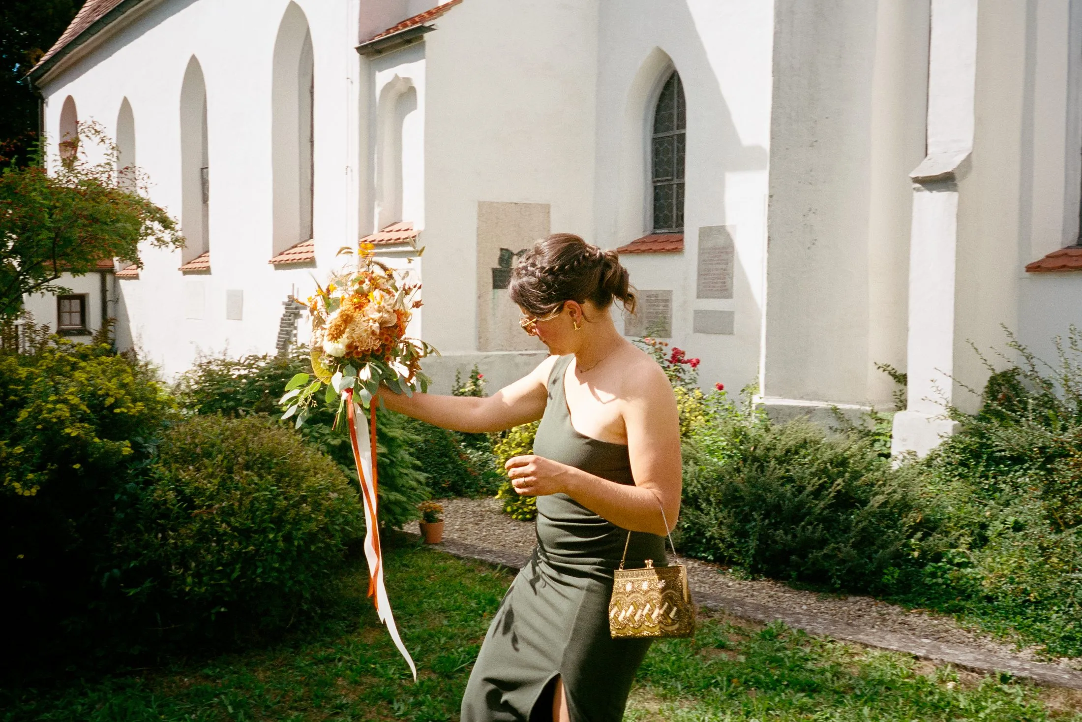 Eine Frau richtet Details von Lisas Kleid vor der Kirche.