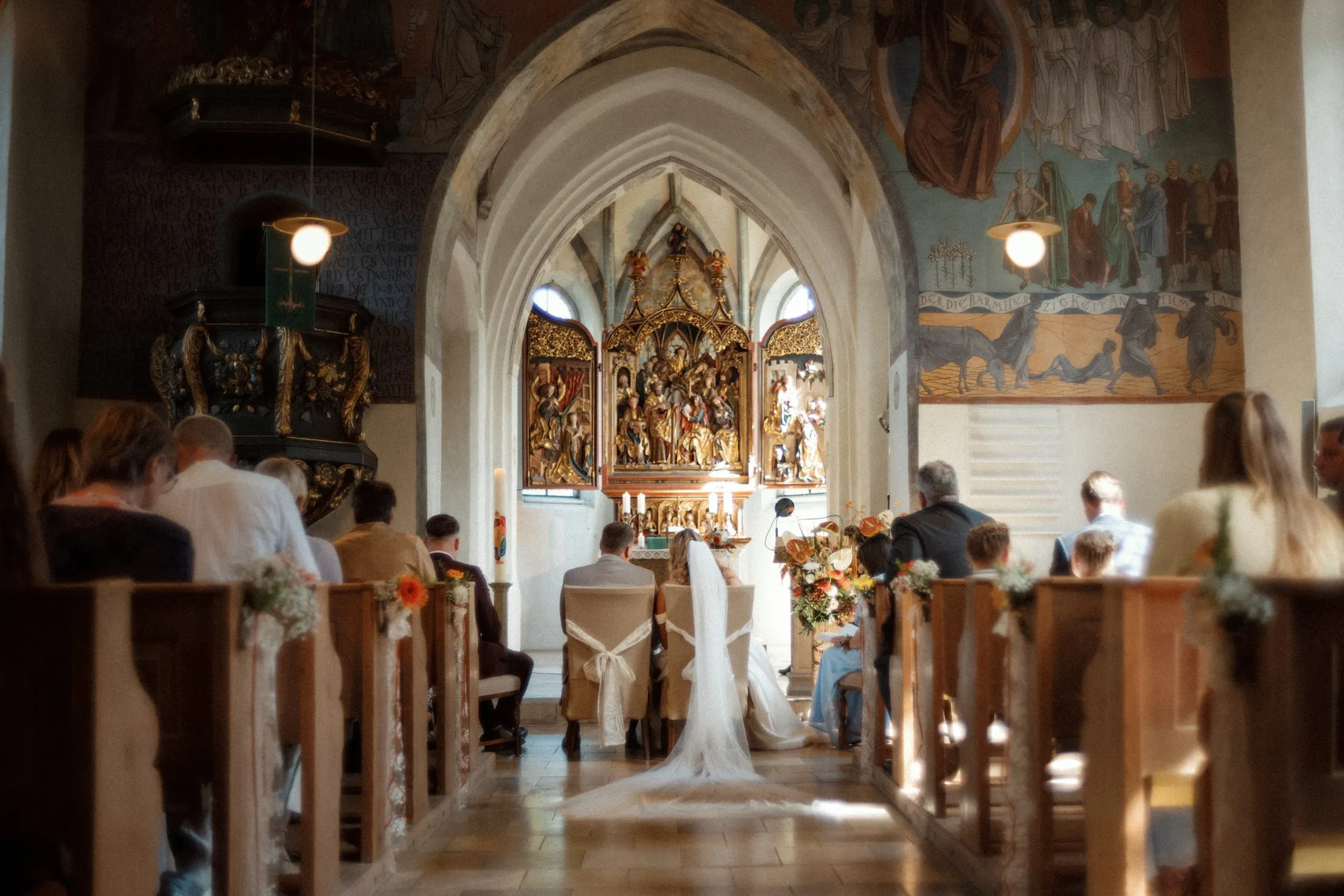Blick durch den Mittelgang auf die Trauung in der Kirche.