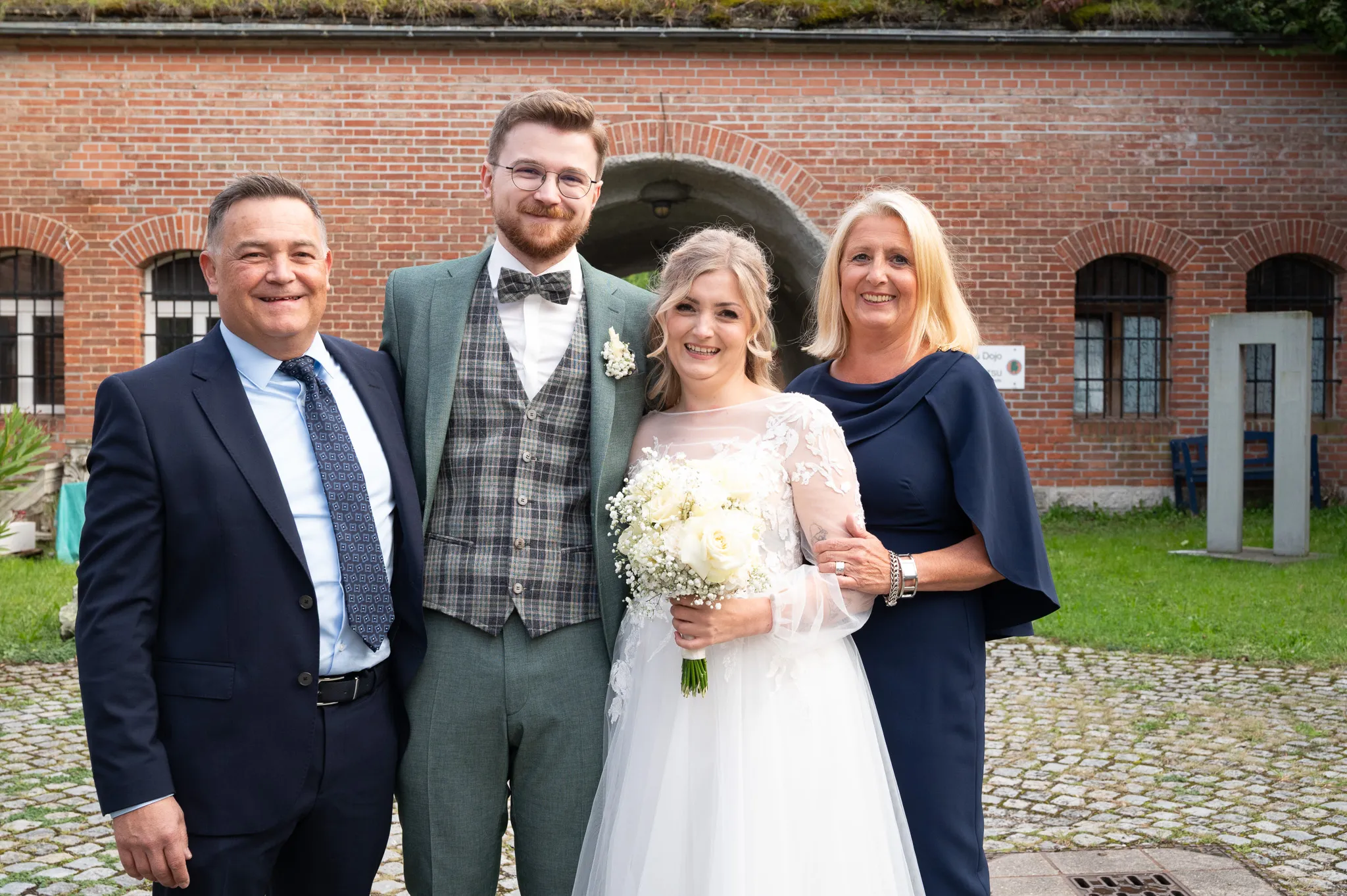 Tamara und Kevin stehen mit zwei Gästen vor dem roten Backsteingebäude.