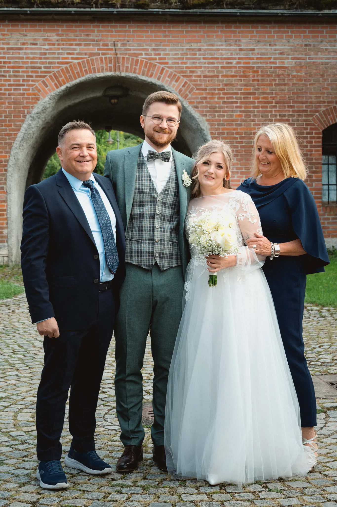 Tamara und Kevin stehen mit zwei Gästen unter einem gemauerten Torbogen.