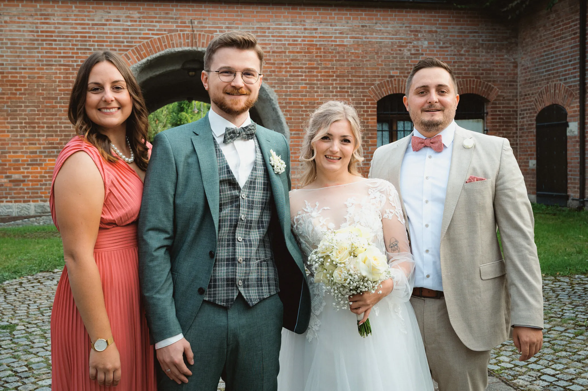 Tamara und Kevin stehen mit einer Gästin im roten Kleid und einem Gast im hellen Anzug zusammen.