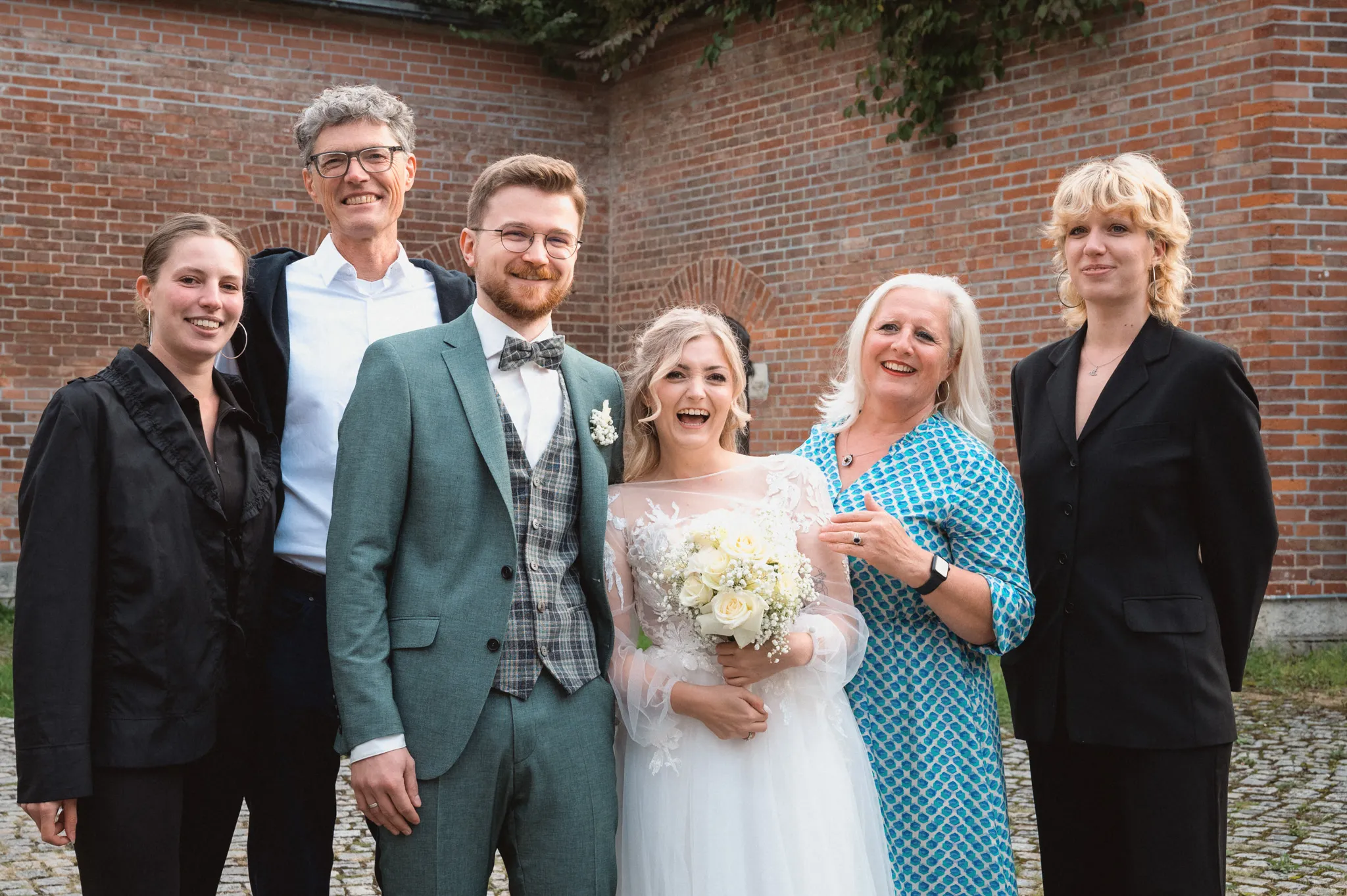 Tamara und Kevin lachen mit mehreren Gästinnen bei einem Gruppenbild.