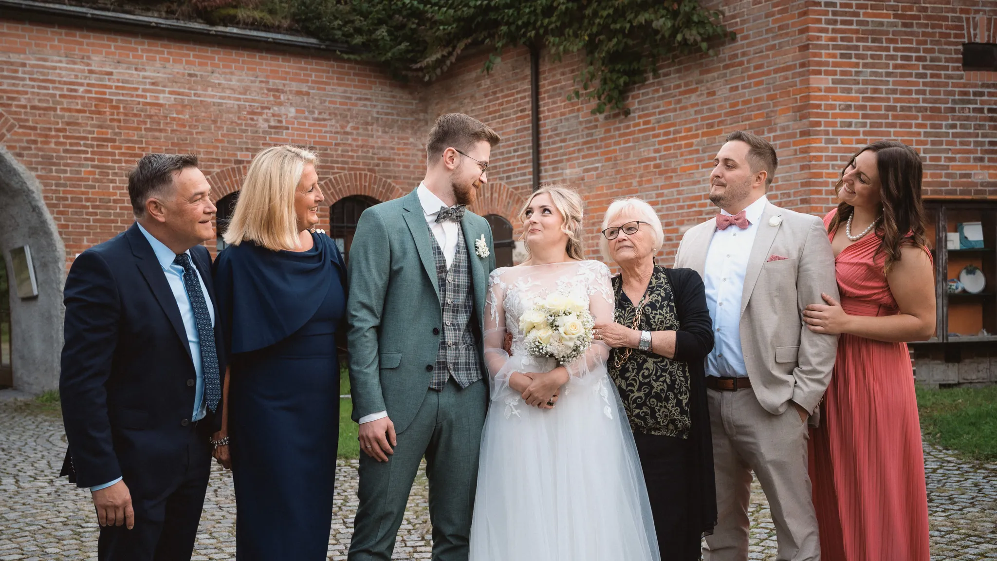 Tamara und Kevin unterhalten sich lachend mit vier Gästen bei einem Gruppenbild.