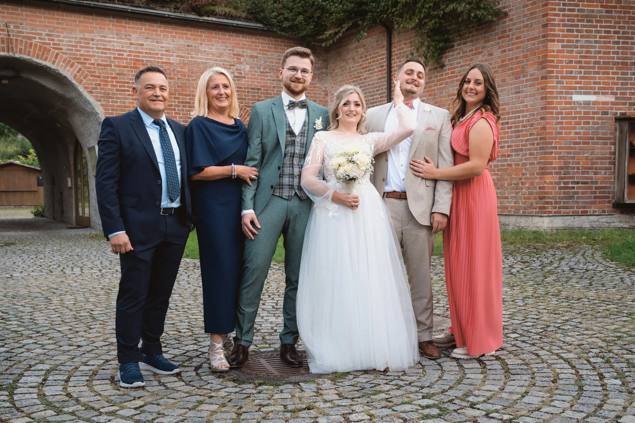 Tamara und Kevin stehen mit vier Gästen auf dem gepflasterten Innenhof.