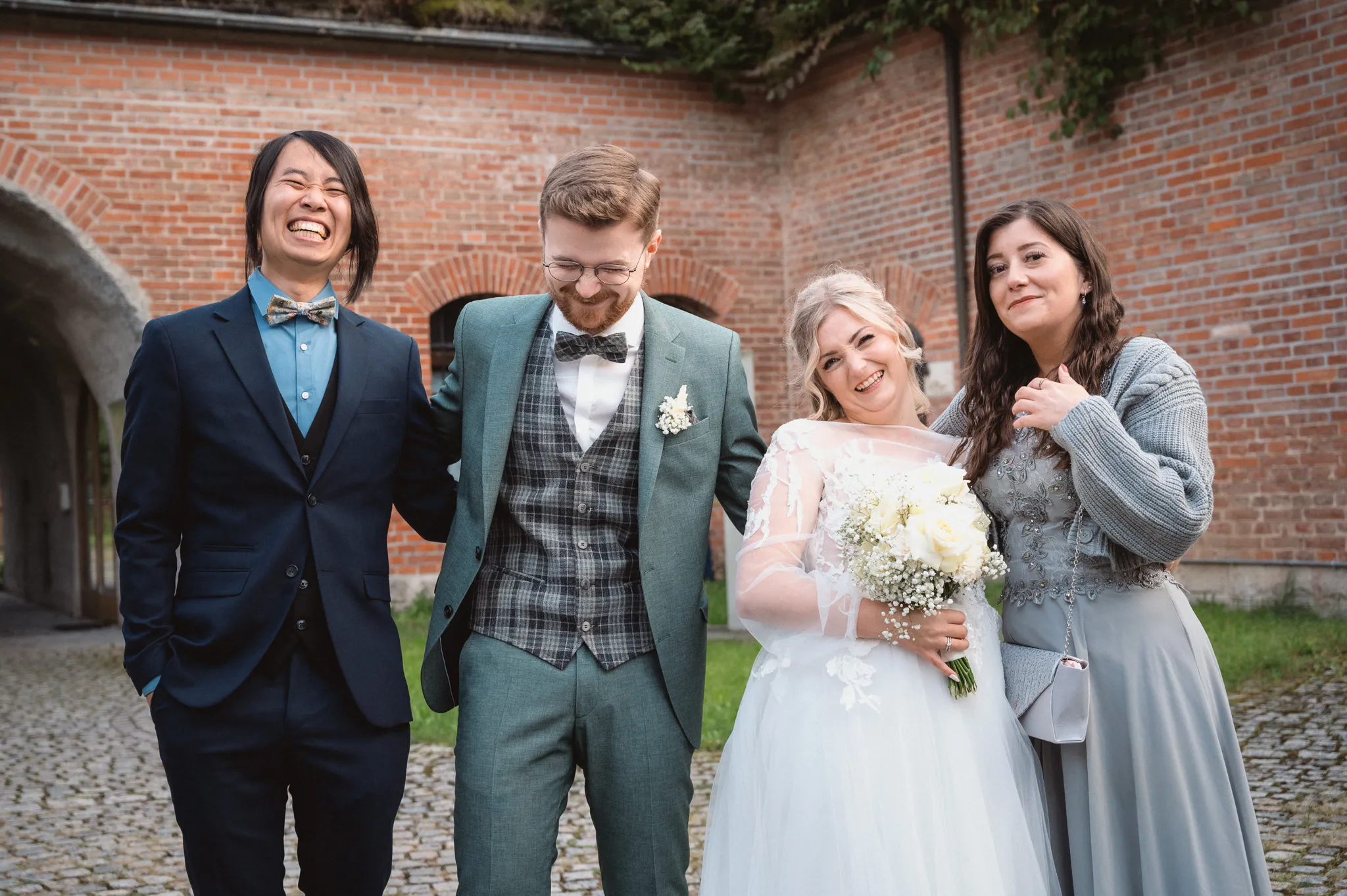 Tamara und Kevin lachen ausgelassen mit zwei Gästen während des Gruppenportraits.