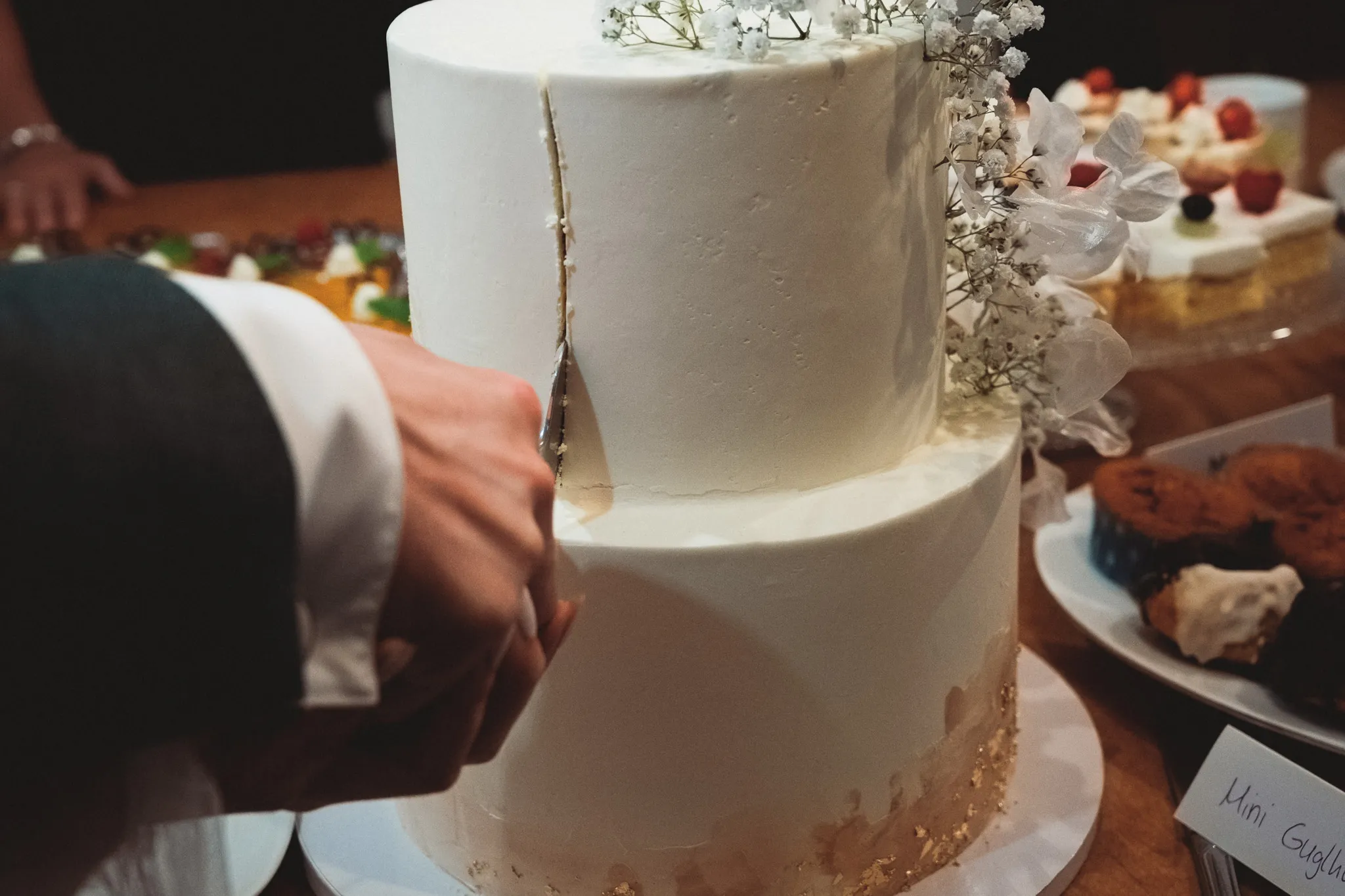 Nahaufnahme eines Messers beim Anschneiden der weißen Hochzeitstorte.