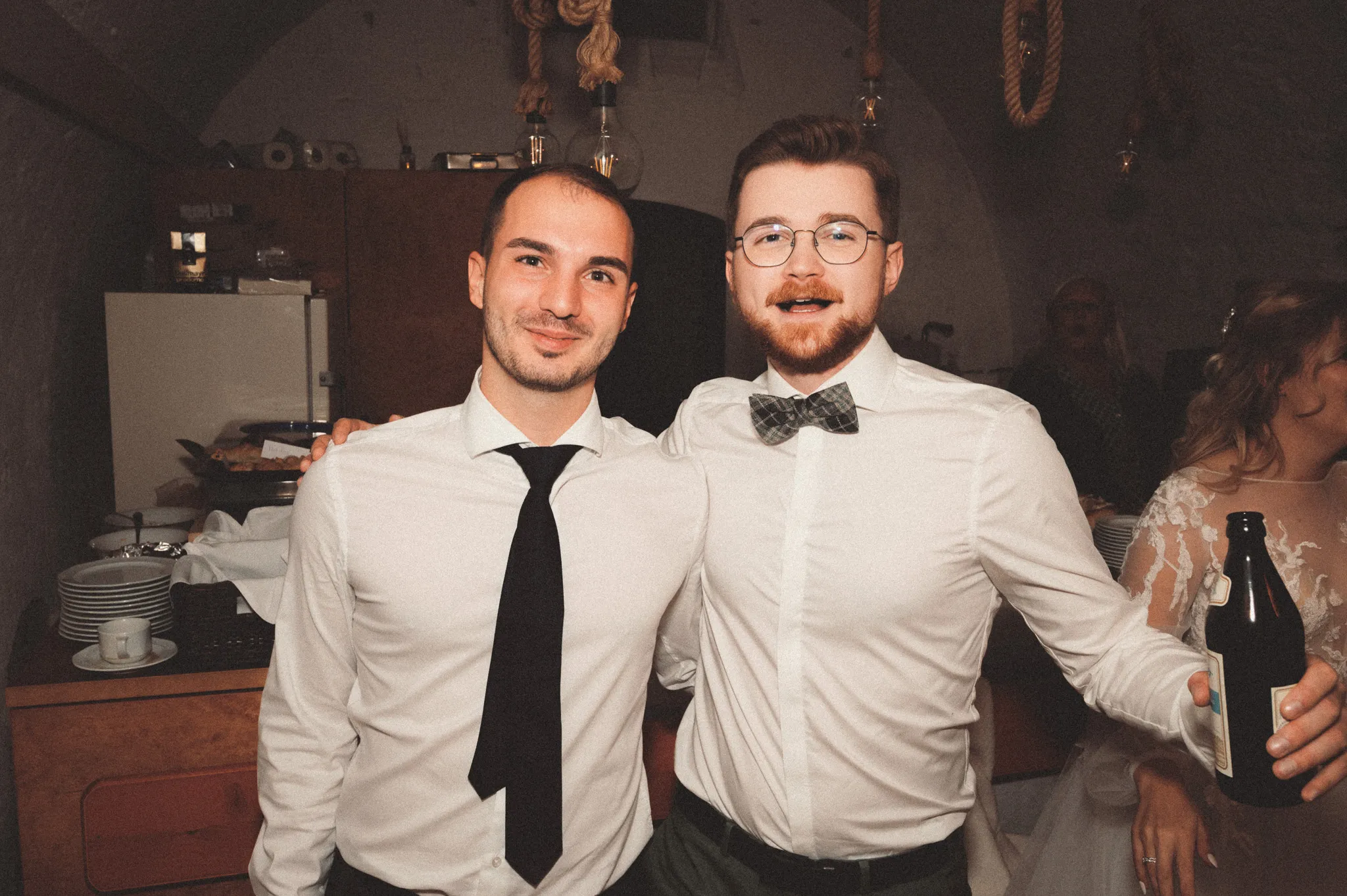 Kevin steht mit einem Gast und Getränken inmitten der Hochzeitsfeier.